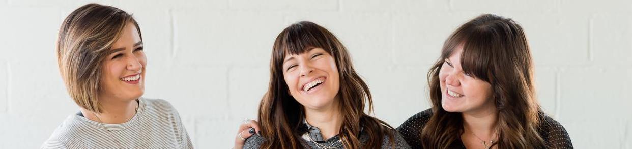 Three women laughing togheter for the shot